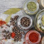 Różne zioła z domowego ogródka leżą w słoiczkach na kuchennym stole